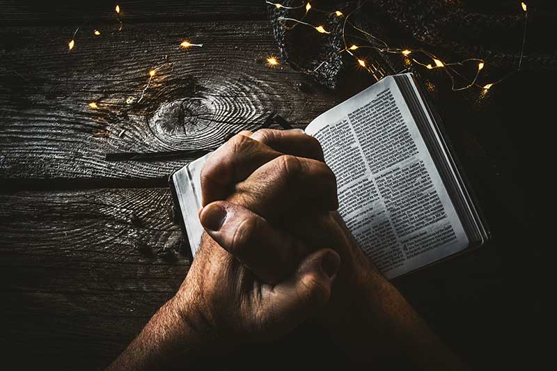 Man praying over Bible in Sun Valley - Jose Mier